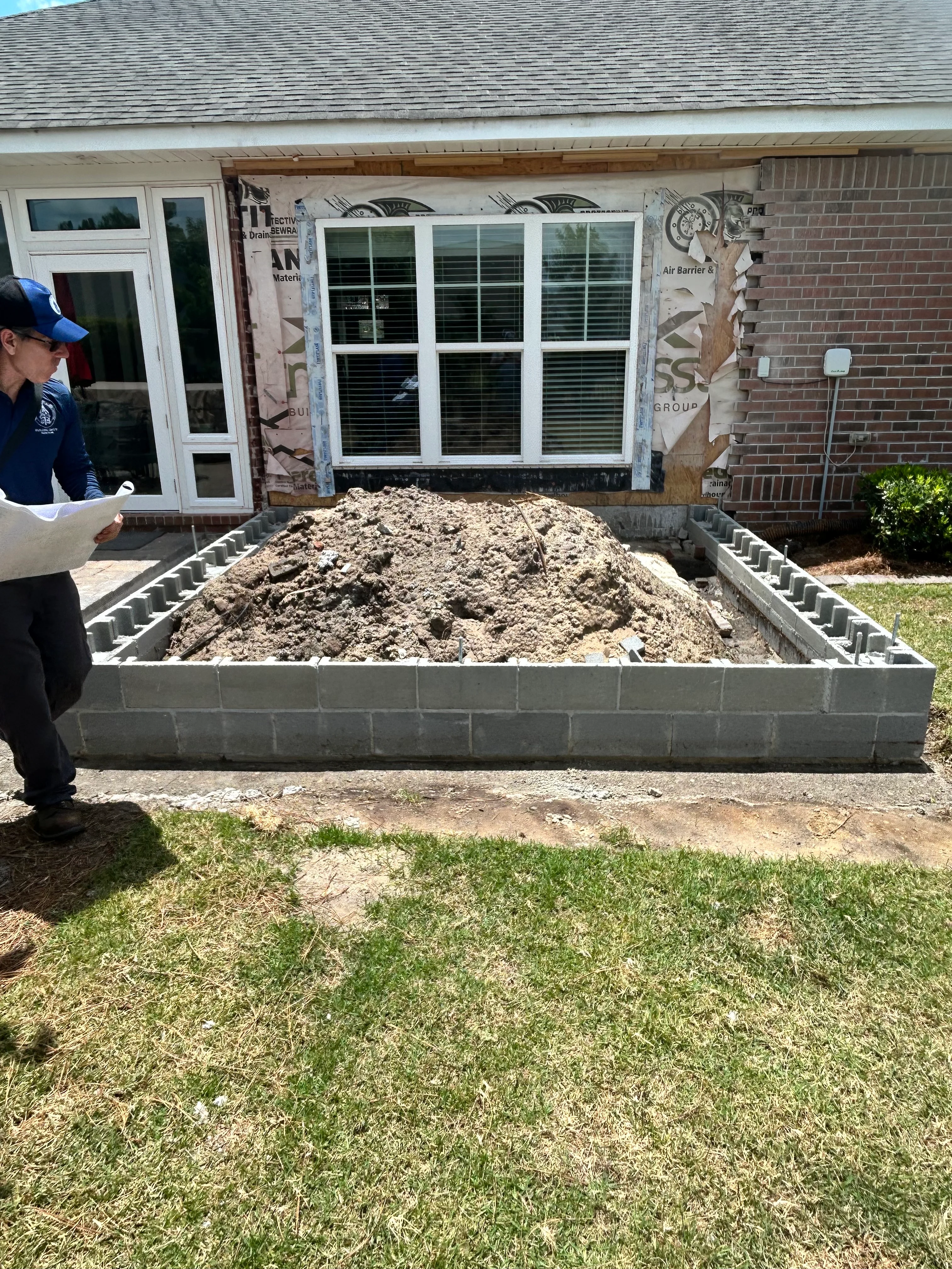 Concrete block foundation wall filled with compacted soil base material for residential construction